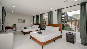 Une chambre d’hôtel avec deux lits, un bureau, une chaise, une table de chevet et une fenêtre avec des rideaux.