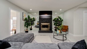 Un salon moderne avec une cheminée, deux canapés, une table basse et des plantes en pot.