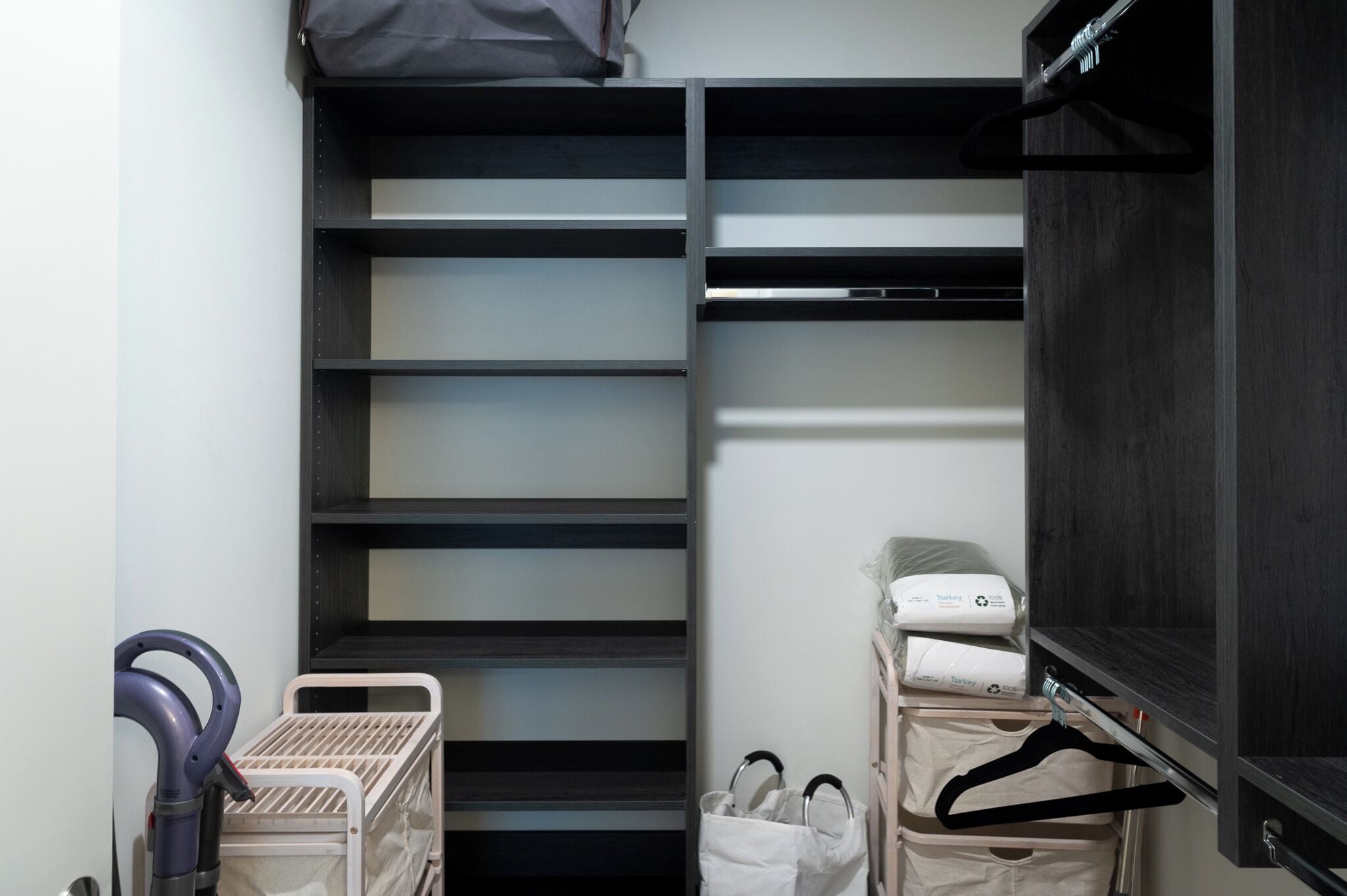 A compact hotel room with a built-in wardrobe, a bed, and a small seating area.
