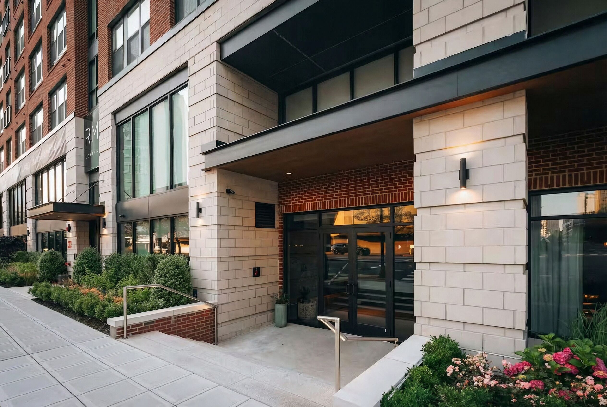 A modern building with a brick facade, large windows, and a well-maintained garden area.
