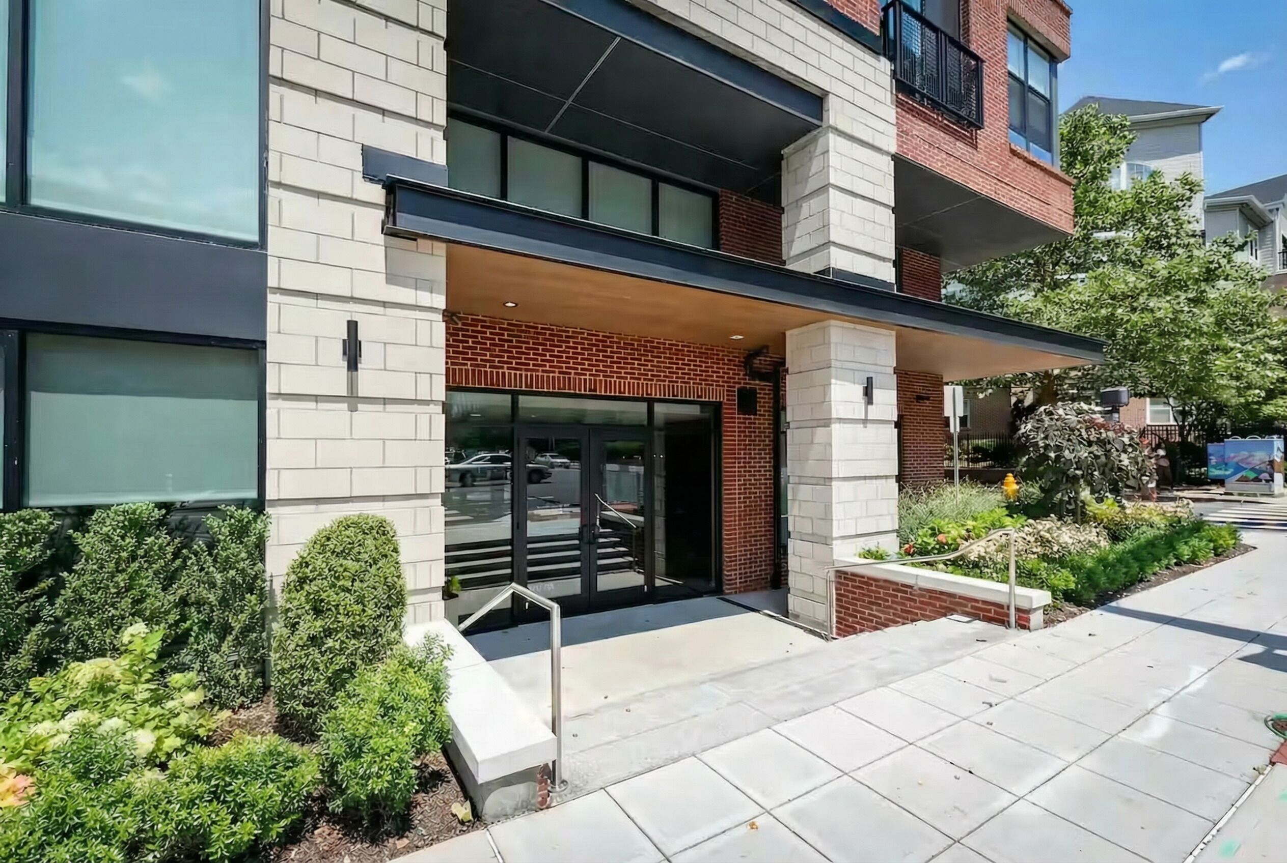 A modern building with a brick facade, large windows, and a covered entrance.