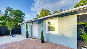 A single-story house with a brick patio, a white door, and a small garden with two potted plants. - Modern Tampa Apartment ~ 3 Mi to Busch Gardens! (Tampa)