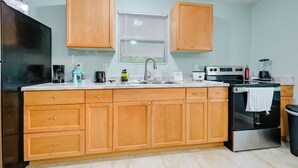 A kitchen with wooden cabinets, a stainless steel refrigerator, a double sink, and a stove. - Modern Tampa Apartment ~ 3 Mi to Busch Gardens! (Tampa)