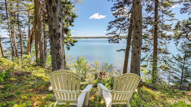 Two Adirondack chairs facing a lake surrounded by trees. - Serene Steuben Home w/ Scenic Ocean Views! (Steuben)