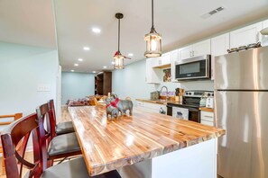 A modern kitchen with a wooden island, stainless steel appliances, and pendant lighting. - Front Royal Studio w/ Mtn Views & Brick Oven (Front Royal)