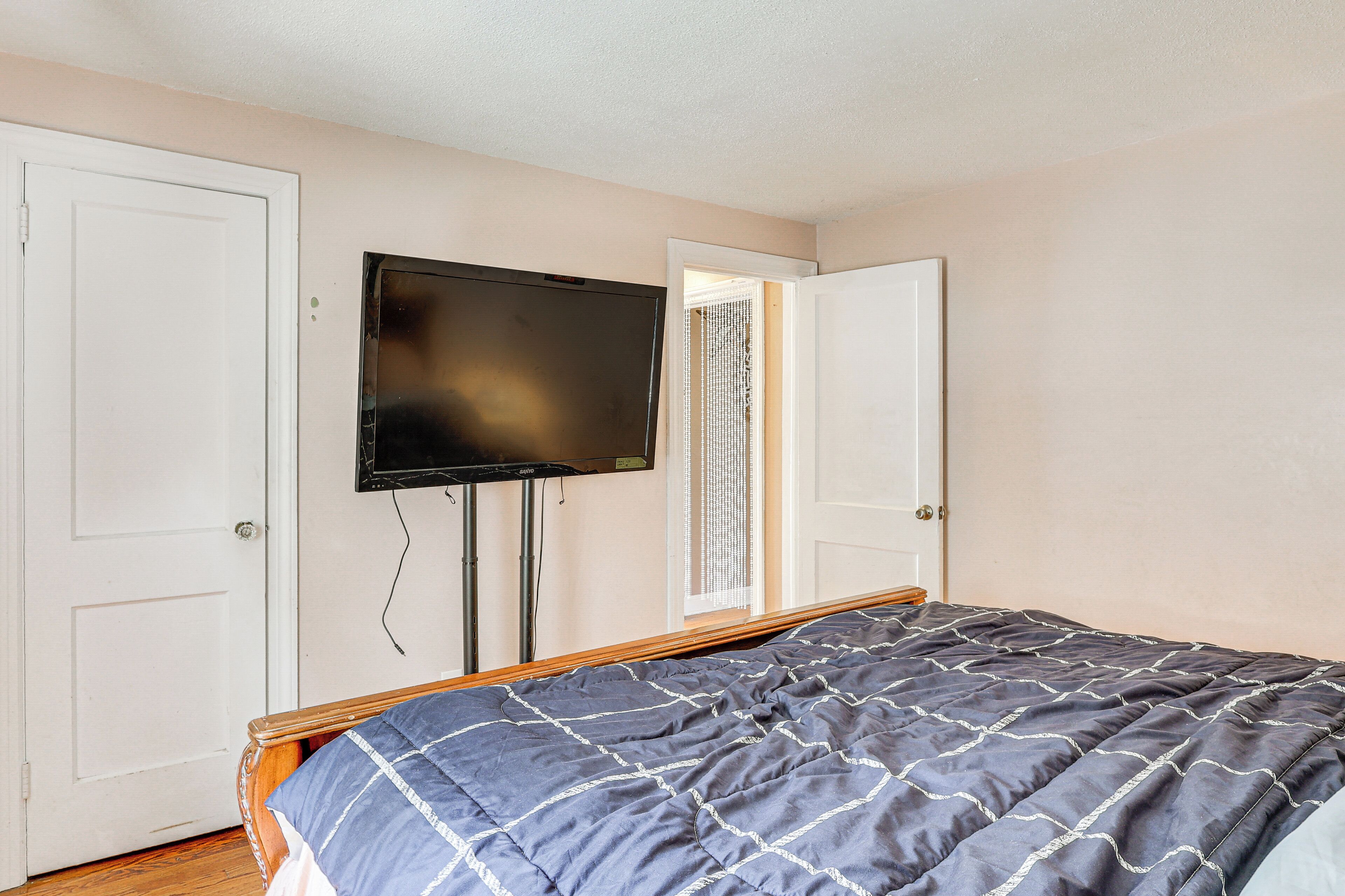 A bedroom with a bed, a television mounted on the wall, and two doors.