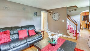 A living room with a black leather sofa, red cushions, a coffee table, and a staircase leading to another room. - Bring Your Pet & Visit Springfield: Westfield Home (Westfield)