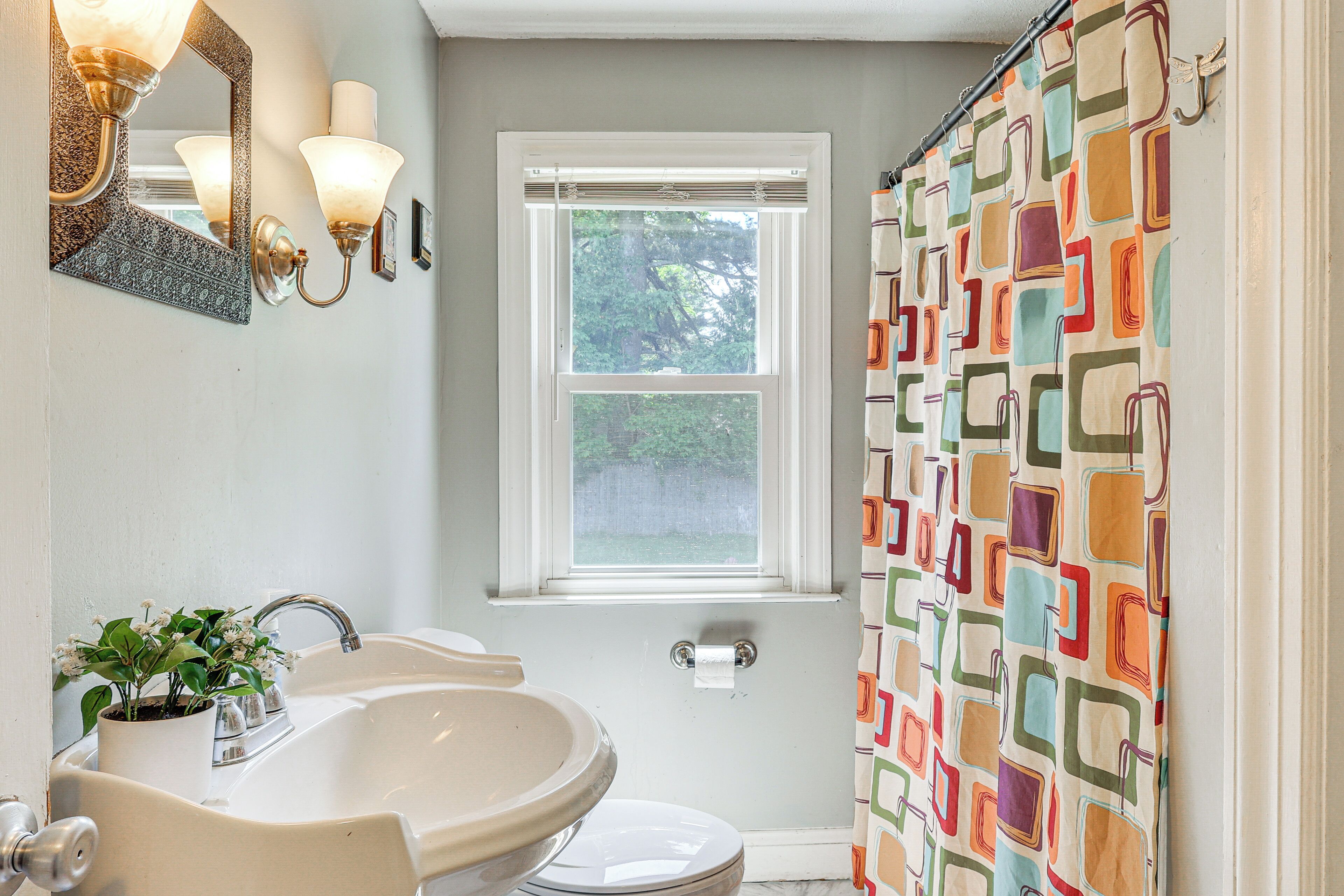 A bathroom with a sink, mirror, and window.