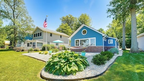 A two-story house with a blue exterior, a front porch, and a flagpole with an American flag. - Waterfront w/ Boat Dock: Retreat on Indian Lake (Belle Center)