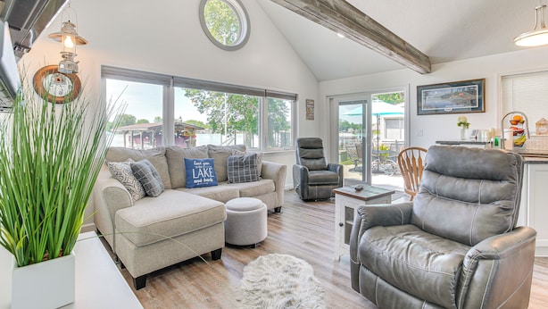 A spacious living room with a high ceiling, a fireplace, and a view of the outdoors. - Waterfront w/ Boat Dock: Retreat on Indian Lake (Belle Center)