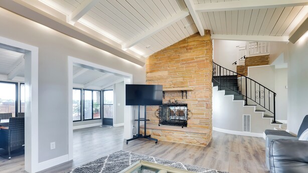A spacious living room with a stone fireplace, a flat-screen TV, a staircase, and a leather couch. - 16 Mi to Manatee Viewing! Spacious Tampa Retreat (Tampa)