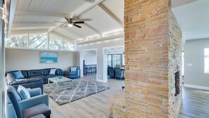 A spacious living area with a brick fireplace, a ceiling fan, and a large window providing natural light. - 16 Mi to Manatee Viewing! Spacious Tampa Retreat (Tampa)