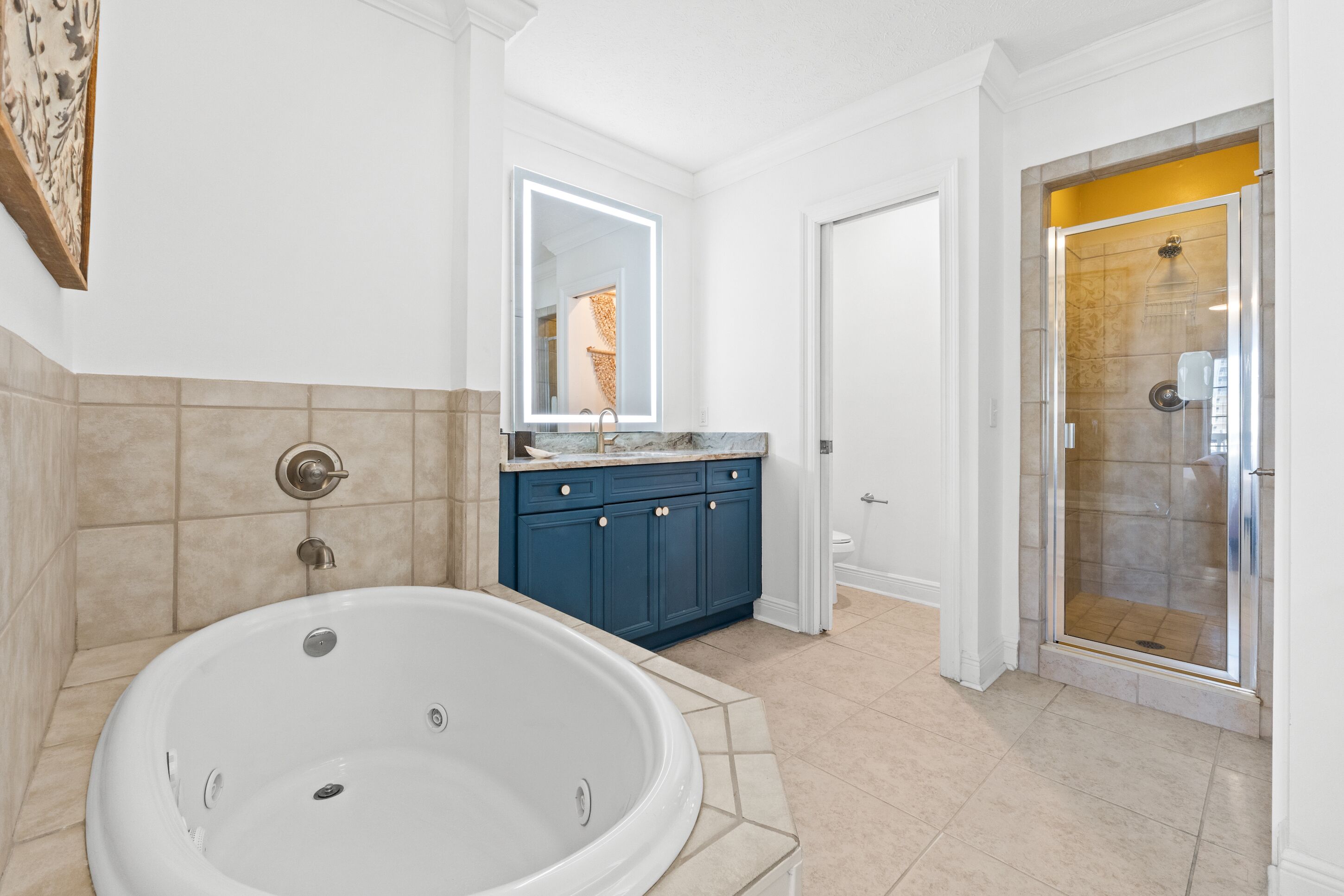 A bathroom with a large bathtub, a vanity with a mirror, and a glass-enclosed shower.