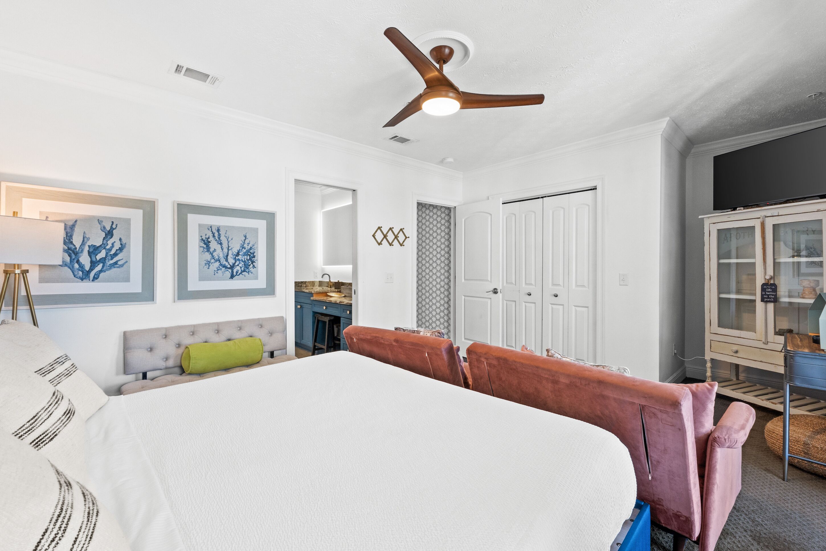 A bedroom with a bed, a ceiling fan, a dresser, and a TV on a cabinet.