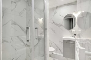 Familie appartement | Badkamer | Een douche, een haardroger, handdoeken, zeep
