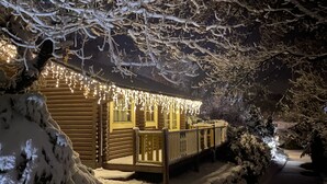 Une cabane en rondins avec une terrasse en bois et un paysage enneigé.