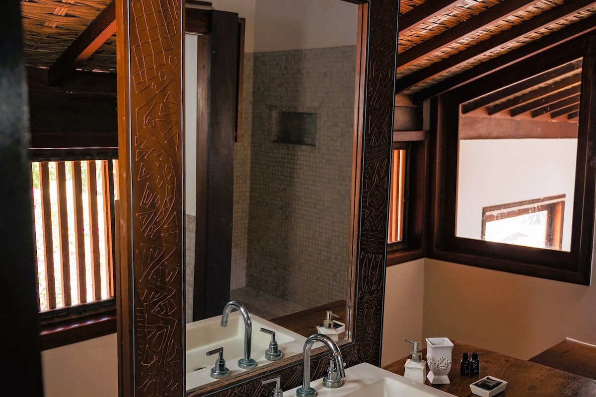Un baño con un espejo grande, un lavabo blanco y dos toallas enrolladas sobre el mostrador.