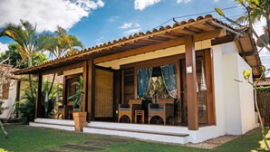 Un área de estar al aire libre techada con una pérgola de madera, una mesa pequeña y sillas.