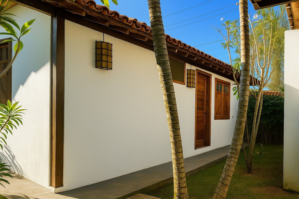 Un edificio blanco con techo de tejas, puertas de madera y una ventana pequeña.