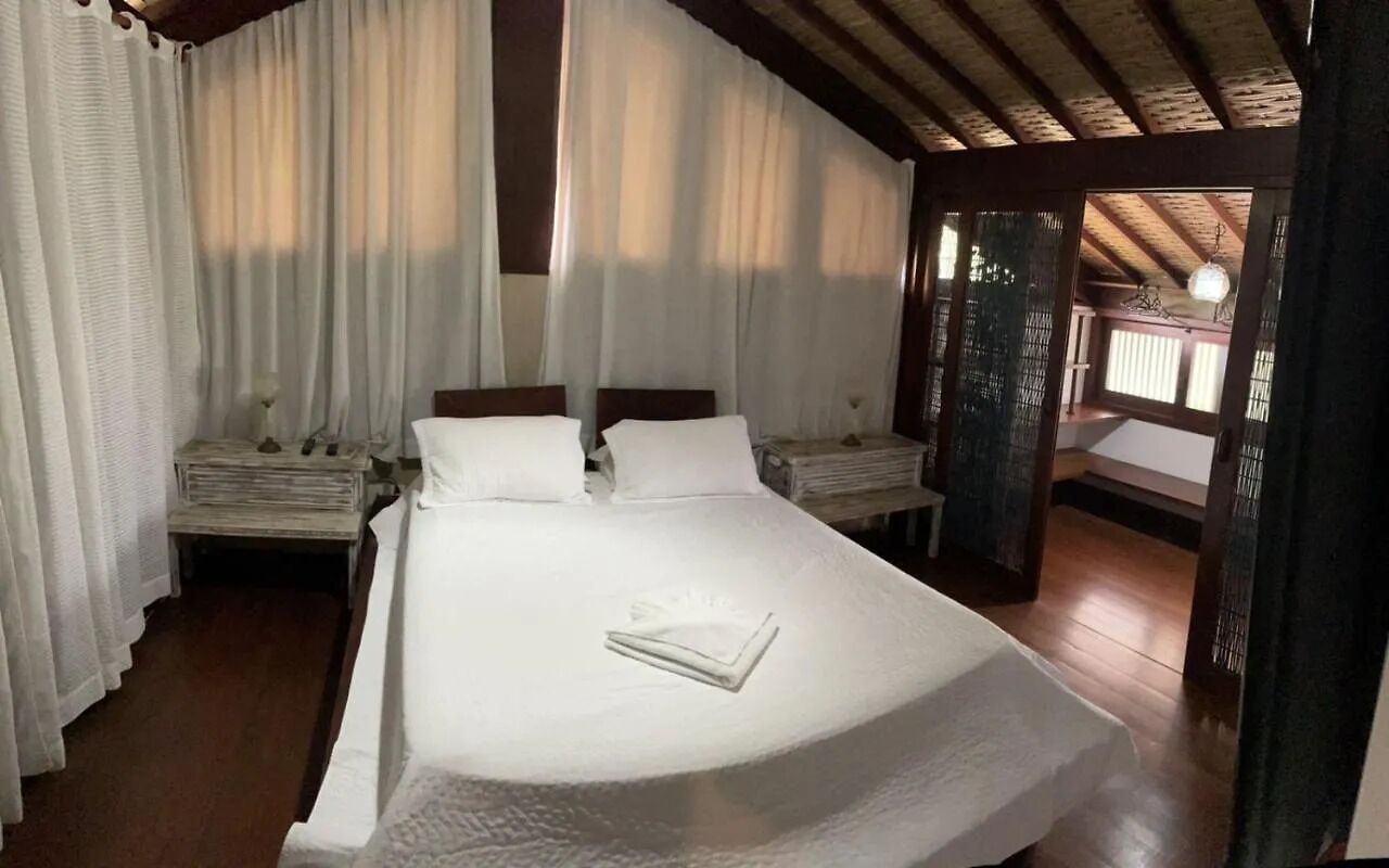 A bedroom with a large bed, two bedside tables, and a view of a wooden deck.