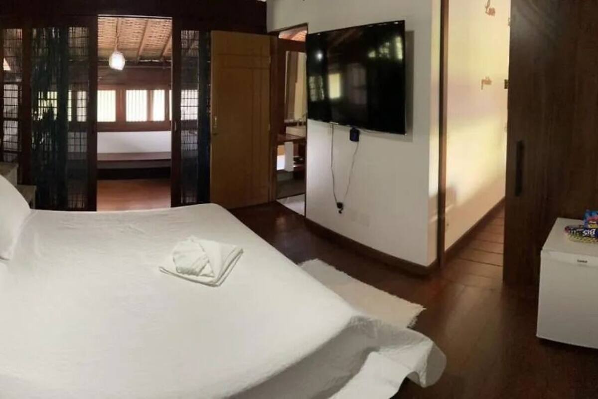 Habitación de hotel con una cama, televisor montado en la pared y un refrigerador pequeño.