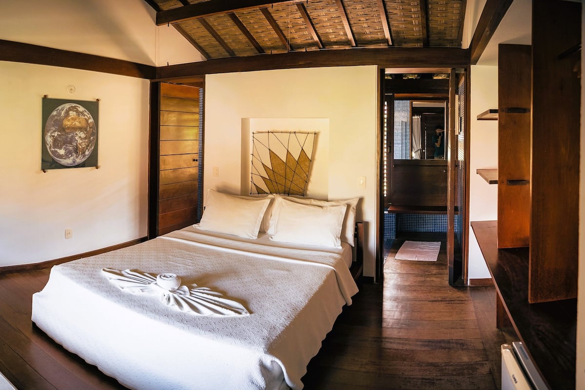 Habitación de hotel con una cama grande, un escritorio y una silla. Hay un televisor en la pared y una ventana con cortinas.