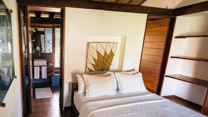 Un dormitorio con techo de madera, cama con ropa de cama blanca, una obra de arte colgada en la pared y cabecero de madera.