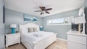 A bedroom with a bed, nightstands, a ceiling fan, a painting, a window, and a TV on a cabinet. - Sunset Sands Retreat #4-Beachfront–Sleeps 4 (Fort Walton)