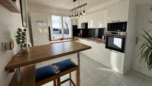 A modern kitchen with white cabinets, a wooden countertop, and a built-in oven. - CAP PLAGE 10 minutes' walk  (AUDIERNE)