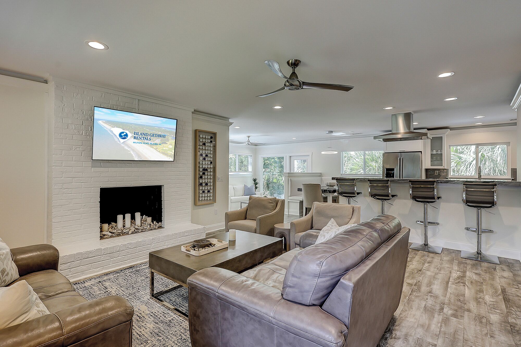 A modern living room with a fireplace, a television mounted on a brick wall, and a bar area with stools.