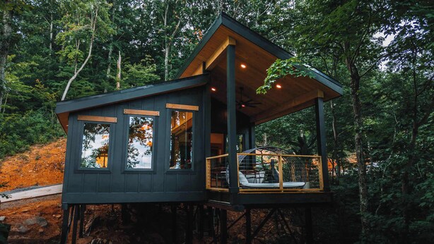 A cabin with a wooden exterior, large windows, and a balcony with seating. - Autumn Blaze at Maple Treehouse (Wildwood)