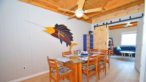 A dining area with a wooden table and chairs, a ceiling fan, and a decorative fish wall art piece. - Sea Edge 3-Oceanfront 36th St, W/D, AC, Free WIFI (Ocean City)