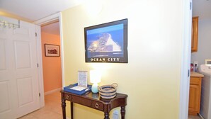 A hallway with a framed picture of Ocean City, a small table with a lamp, and a basket.