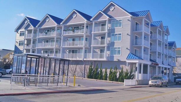 A multi-story hotel with balconies, a covered entrance, and a parking area.