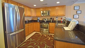 A modern kitchen with stainless steel appliances, wooden cabinets, and a granite countertop.