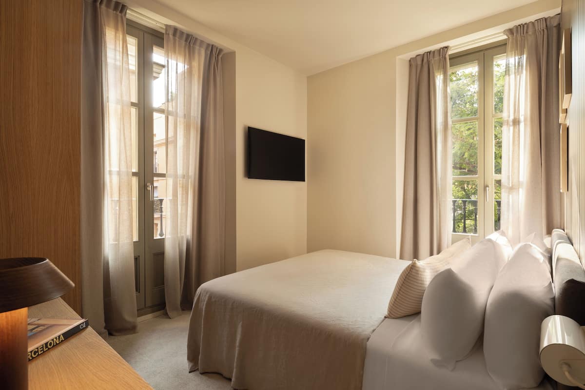 Een hotelkamer met een bed, gordijnen, een flatscreen televisie en een raam met uitzicht.