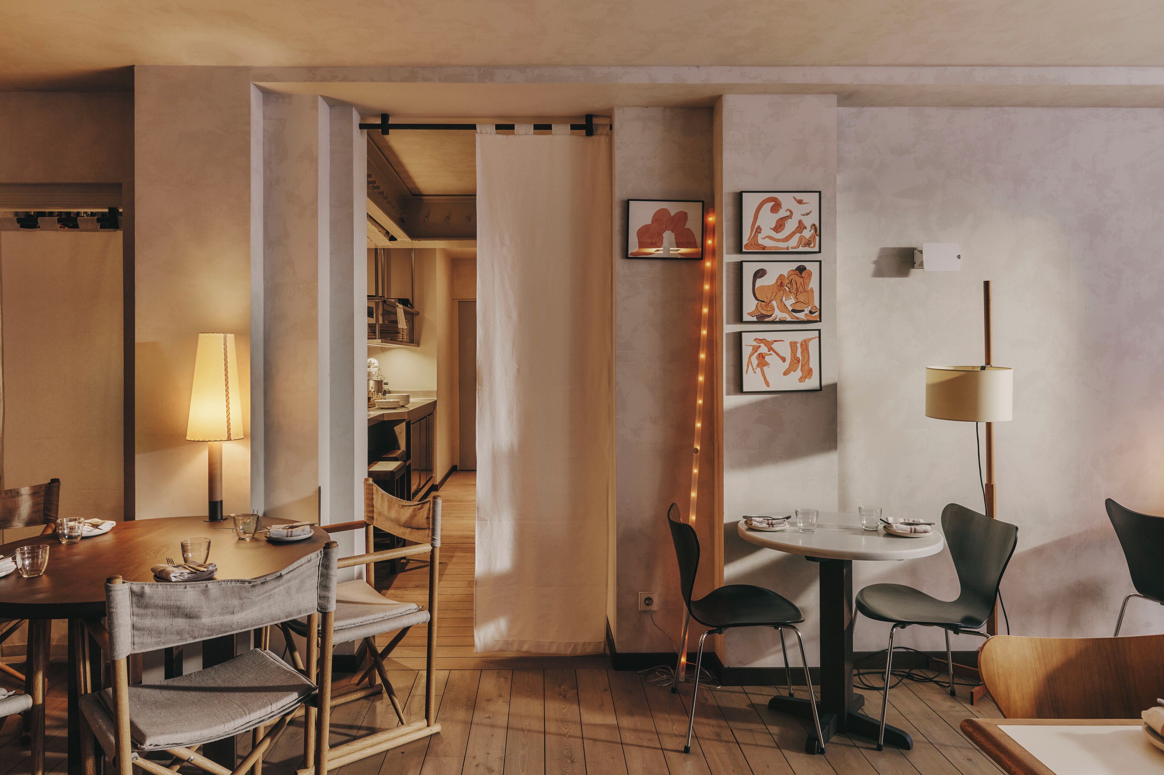 Ein Essbereich mit Holztischen und -stühlen, einer Lampe und gerahmten Kunstwerken an der Wand.
