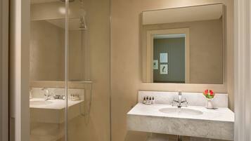 Un baño moderno con ducha de vidrio, un espejo grande y un lavamanos de mármol.
