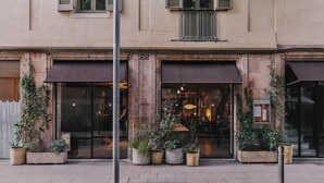 A building with a number 22 sign, large windows, and potted plants in front. - Hotel Casa Teva (Barcelona)