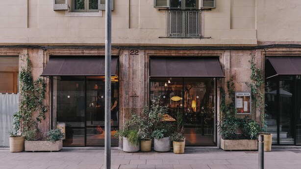 Un edificio con el número 22, ventanas amplias y plantas en macetas al frente.