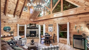 Interior de una cabaña de madera con chimenea, comedor y cocina.