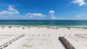 Une plage avec une promenade en bois menant à l’eau, une plage de sable et des parasols.