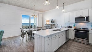Une cuisine moderne avec des meubles blancs, des appareils en acier inoxydable et un grand îlot central doté d’un évier.