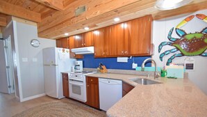 Una cocina con armarios de madera, una estufa, un lavavajillas y un lavabo.