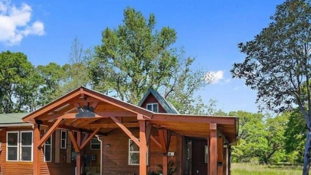 A wooden cabin with a covered porch and a gravel driveway. - Beautiful Cabin in a great neighborhood and minutes from Baton Rouge!! (Denham Springs)