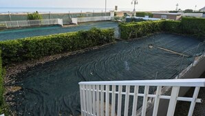 A rooftop pool area with a view of the sea, surrounded by greenery and a white railing. - VILLA MARGHERITA 1 (Lido di Jesolo)