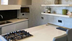 Une cuisine moderne équipée d’une cuisinière à gaz, de meubles blancs et d’un téléviseur encastré.