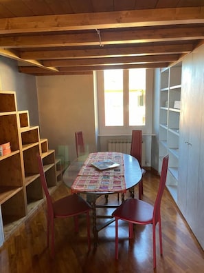 A dining area with a round table, red chairs, wooden shelves, and a window with natural light. - Sea And Park-genoa Nervi - (Genoa)