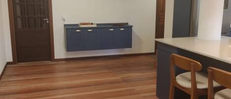 A kitchen with wooden flooring, a blue cabinet, and two wooden chairs.