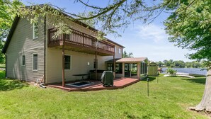 Ein zweistöckiges Haus mit überdachter Veranda, einer kleinen Terrasse und Seeblick.